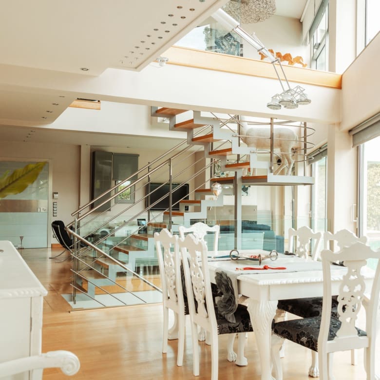 Dining area with double-height space and staircase at a private villa in Alimos, Athens Riviera