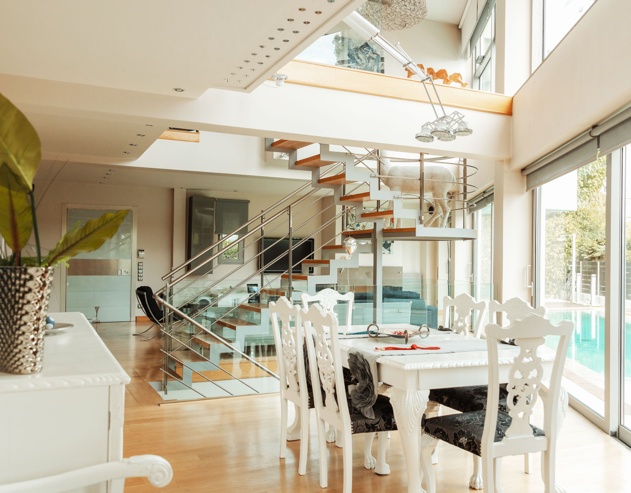 Dining area with double-height space and staircase at a private villa in Alimos, Athens Riviera