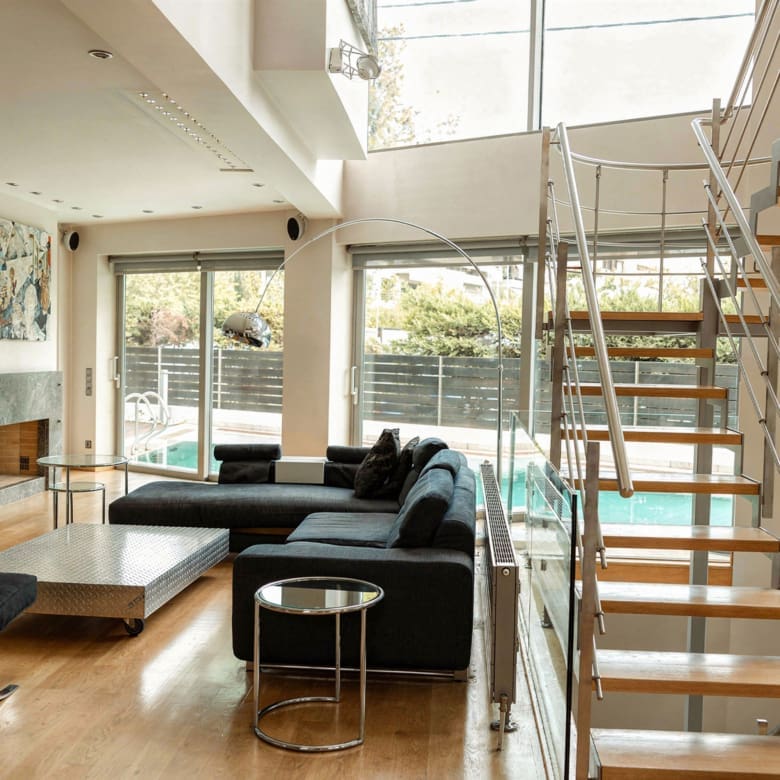 Open-plan living space with staircase and natural light at a private villa in Alimos, Athens Riviera