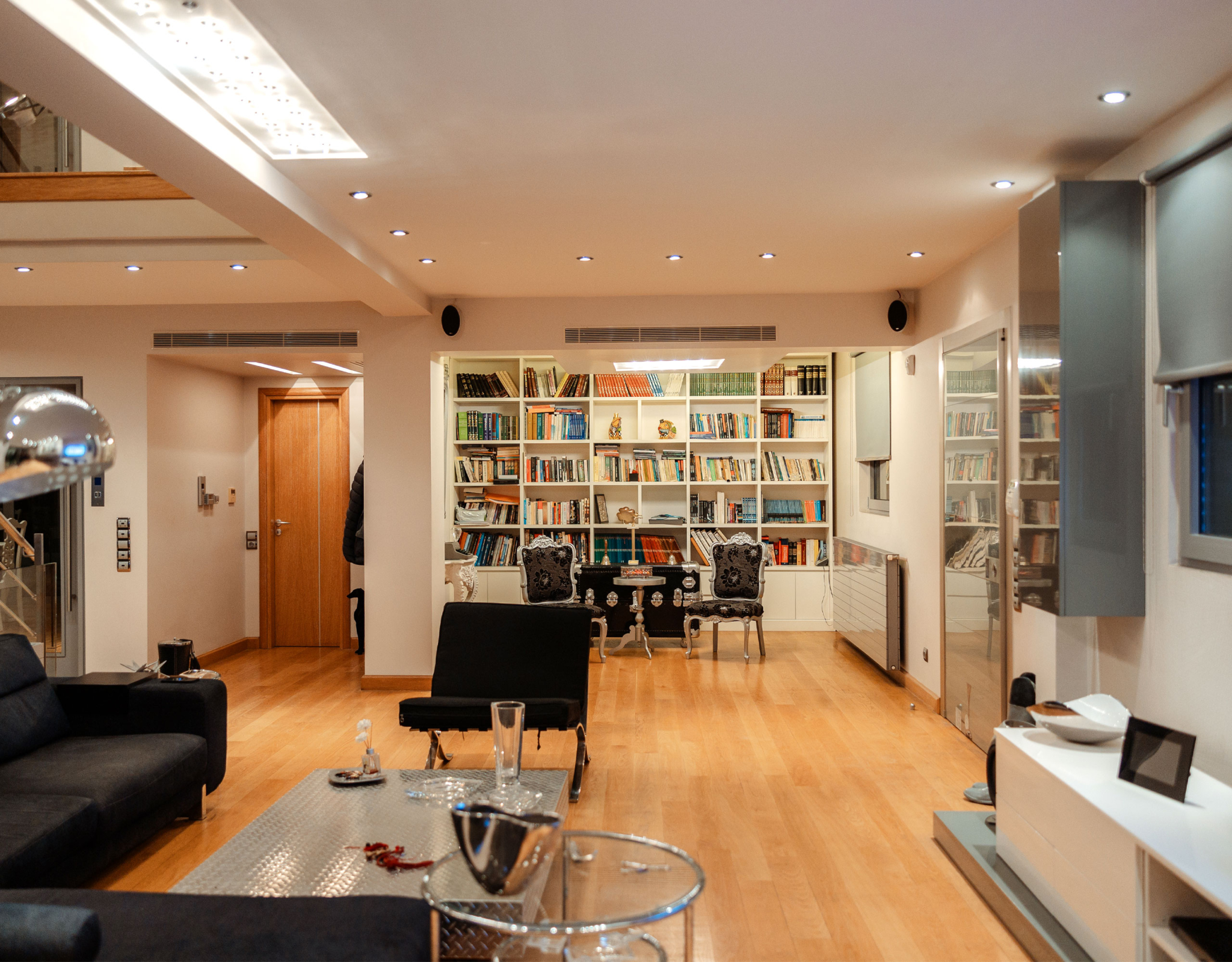 Living area with library wall and open-plan layout at a private villa in Alimos, Athens Riviera