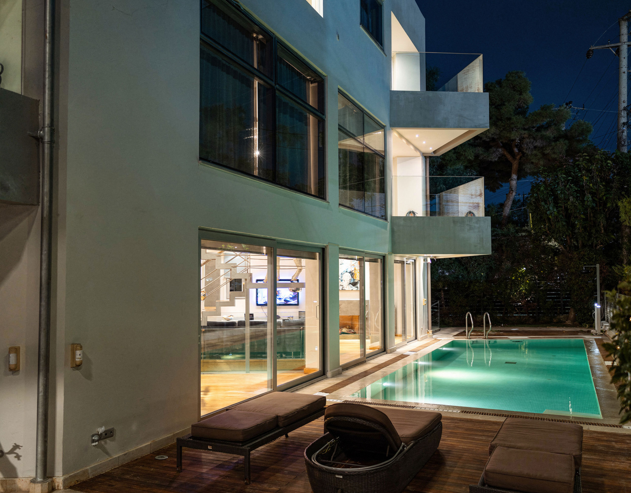 Private pool area at night with illuminated villa façade in Alimos, Athens Riviera