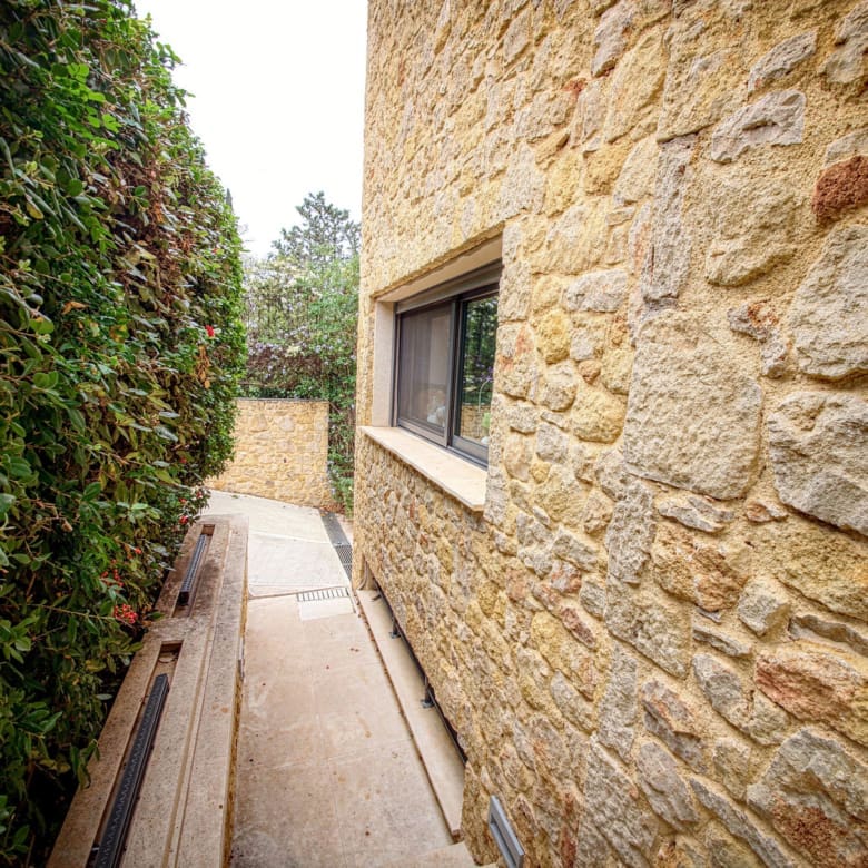Narrow outdoor side passage with stone wall and greenery, Porto Rafti, Greece