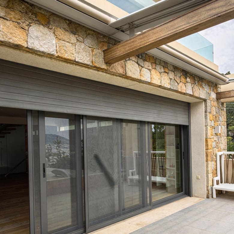 Covered outdoor patio with sliding glass doors and stone facade, Porto Rafti, Greece