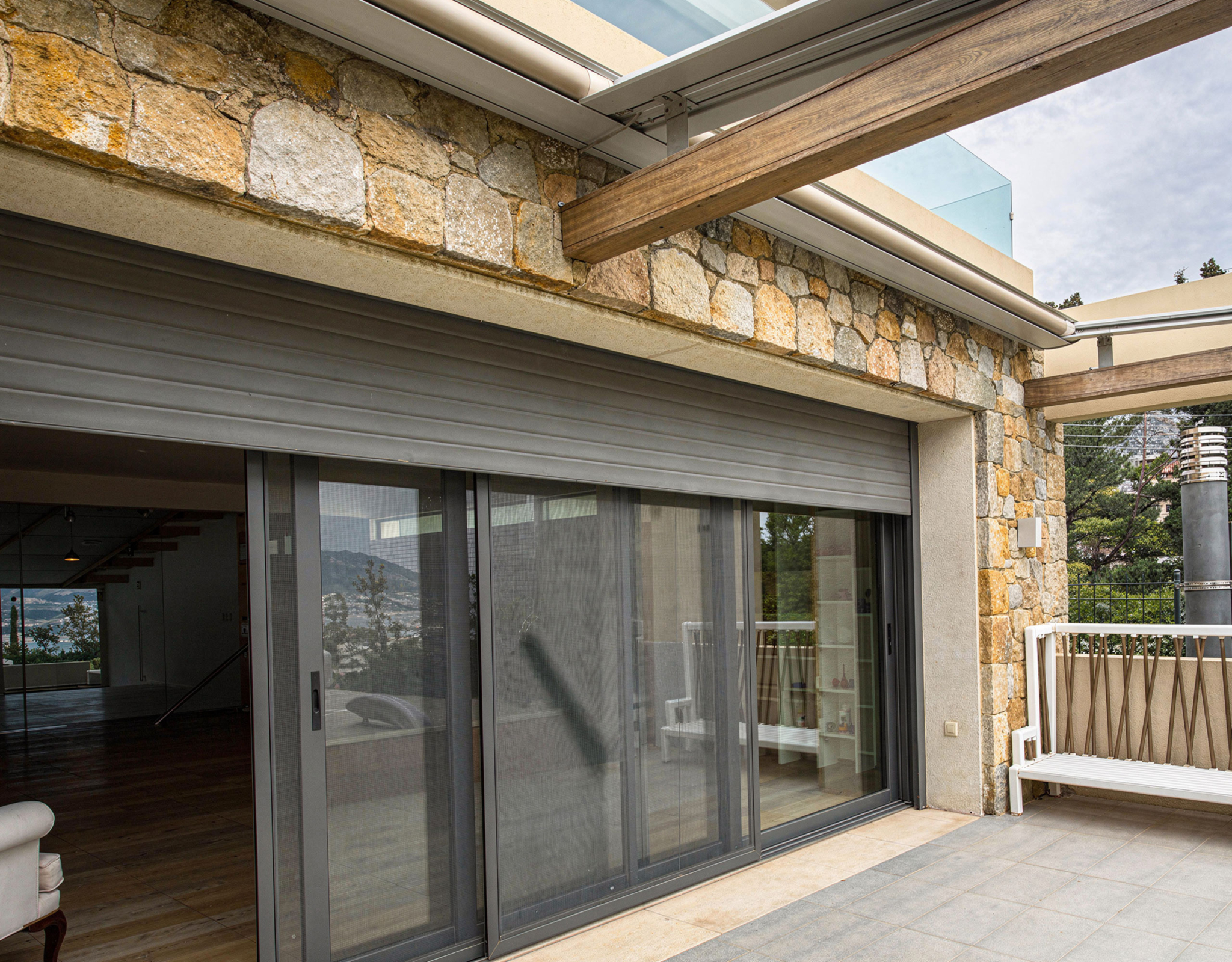 Covered outdoor patio with sliding glass doors and stone facade, Porto Rafti, Greece