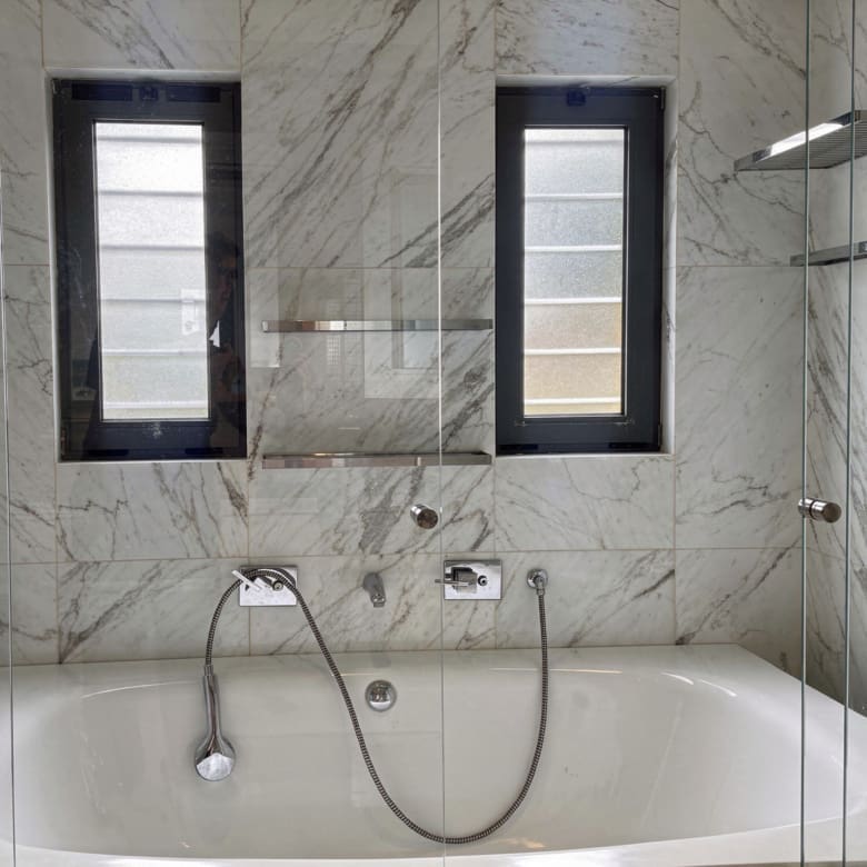 Bathroom with bathtub, marble-look wall tiles, and window, Porto Rafti, Greece