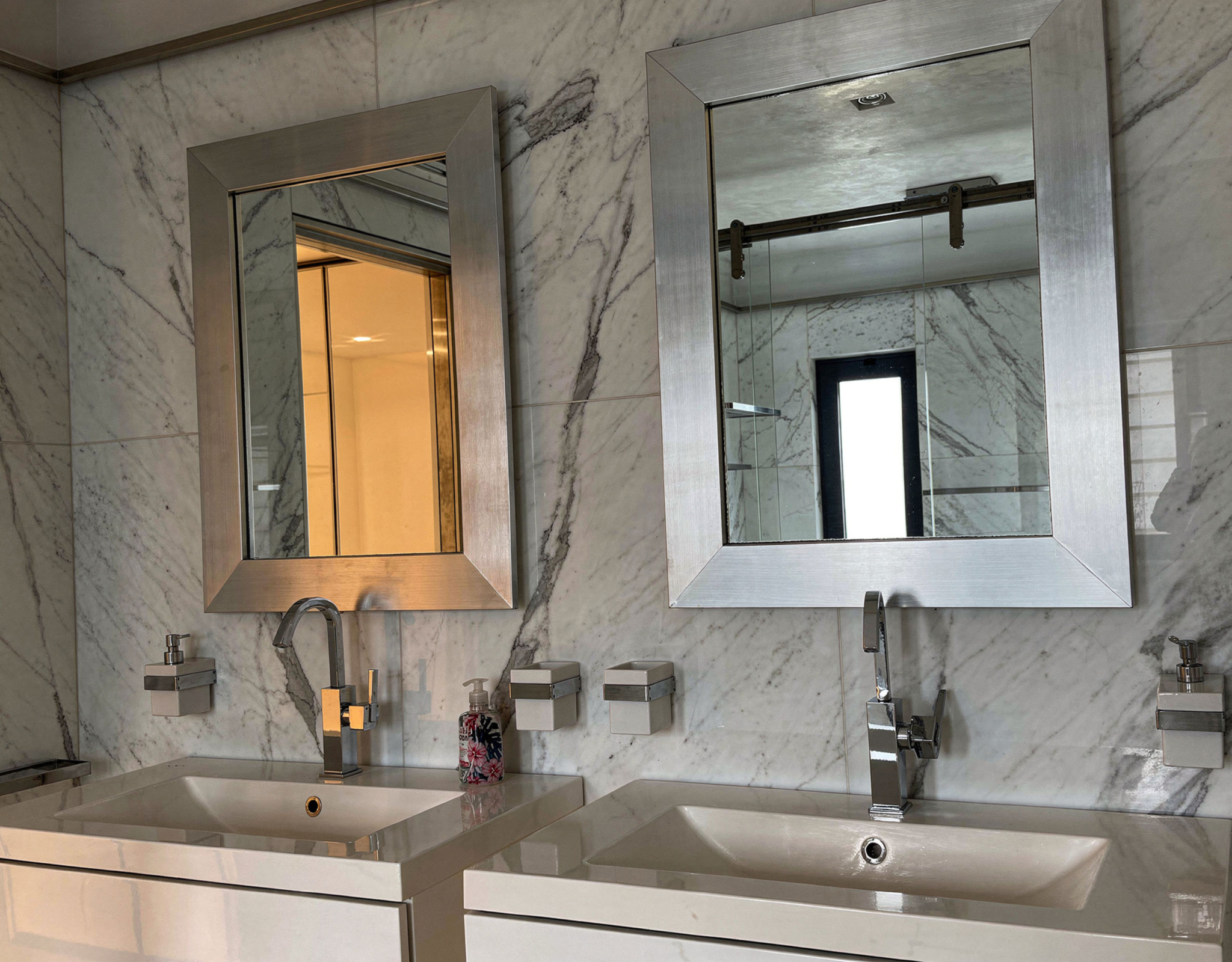 Bathroom vanity with double sink, mirror, and marble-look wall tiles, Porto Rafti, Greece