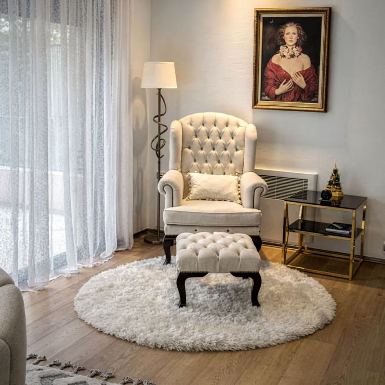 Sitting area with armchair, side table, and soft daylight through curtains, Porto Rafti, Greece