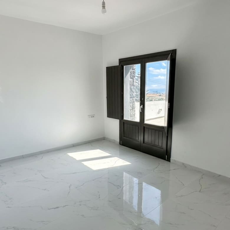 Bright bedroom with balcony door in the Exo Gonia sea-view apartment, Santorini
