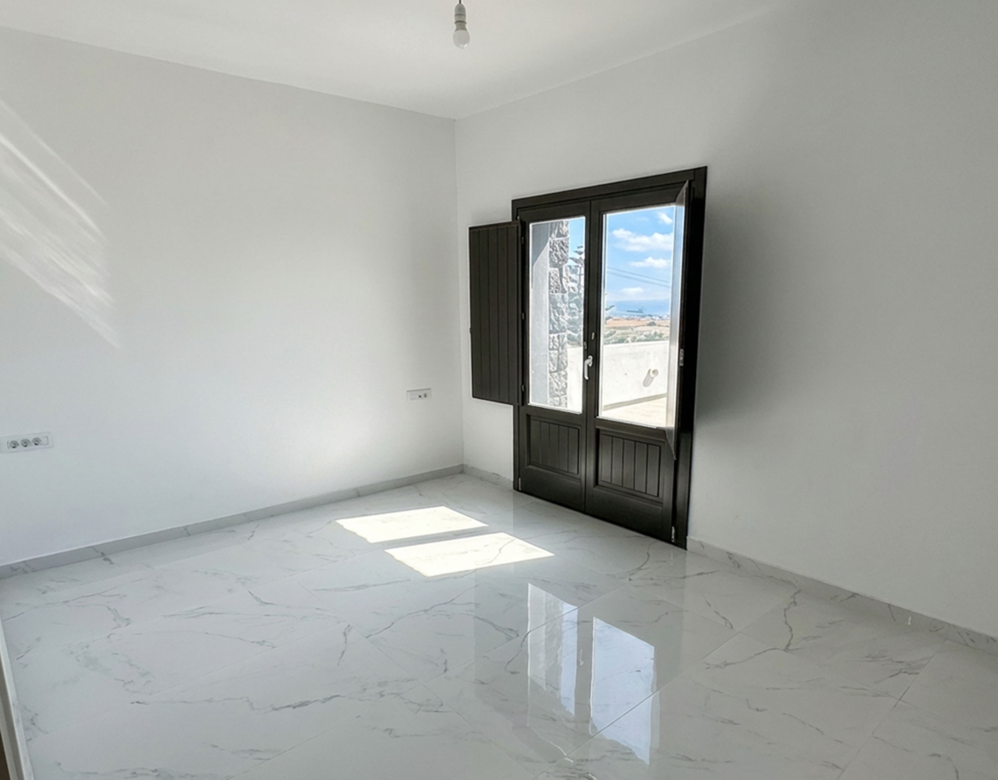 Bright bedroom with balcony door in the Exo Gonia sea-view apartment, Santorini