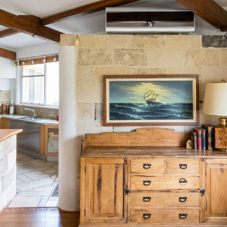 Interior corner with stone wall, timber beams, and kitchen view at a private estate in Porto Rafti, Attica