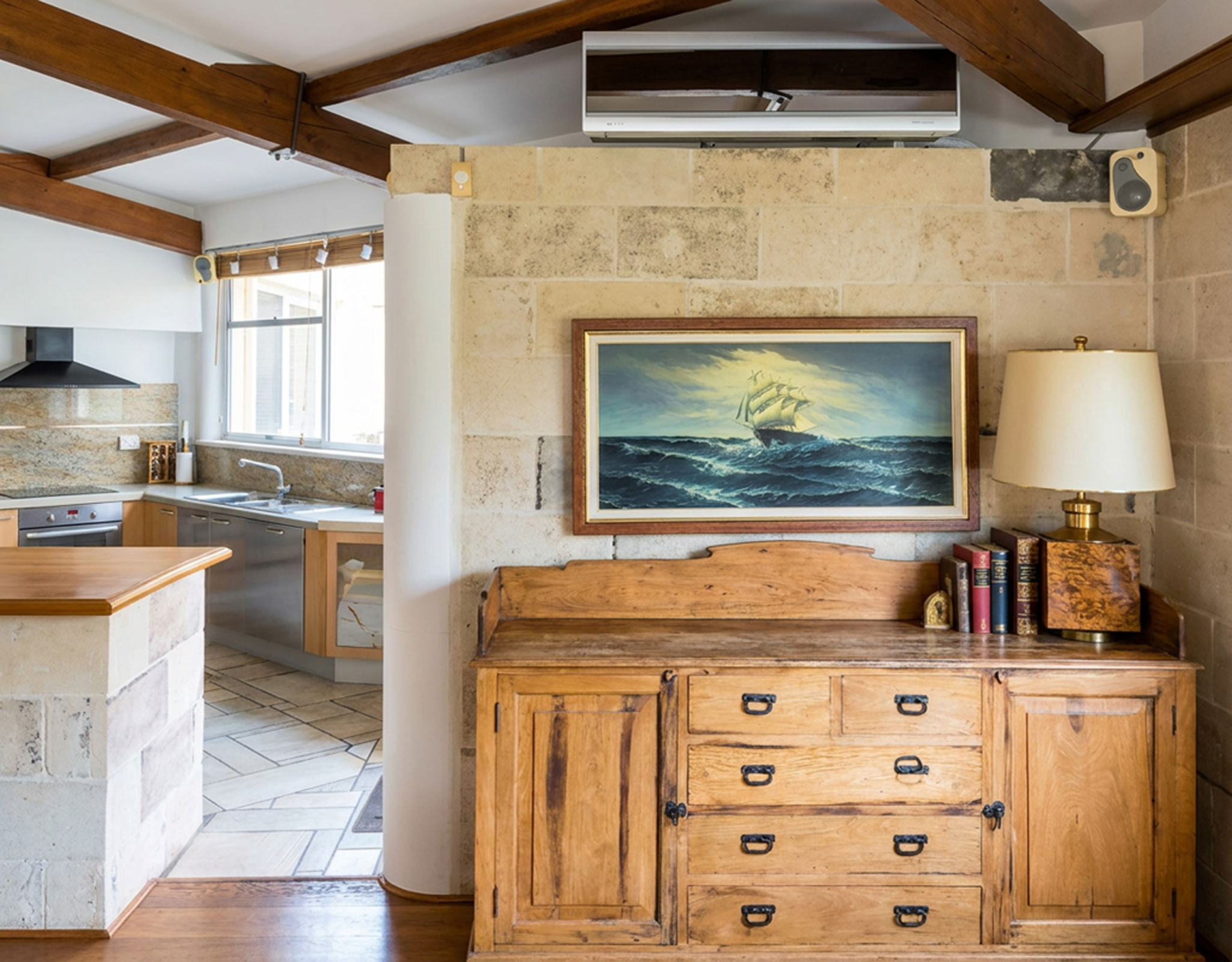 Porto Rafti Estate – Interior Detail with Timber Beams Interior corner with stone wall, timber beams, and kitchen view at a private estate in Porto Rafti, Attica