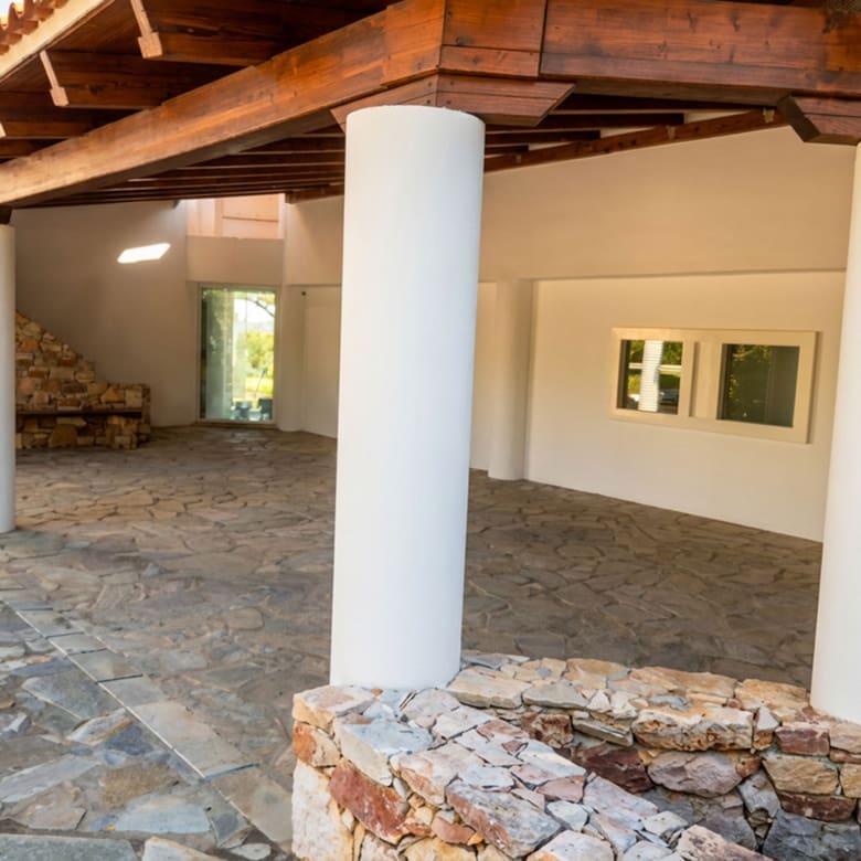 Covered outdoor walkway with stone flooring and columns at the Porto Rafti private estate
