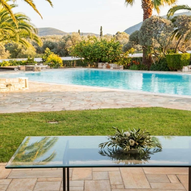 Covered terrace with table overlooking the swimming pool and garden in Porto Rafti, Attica