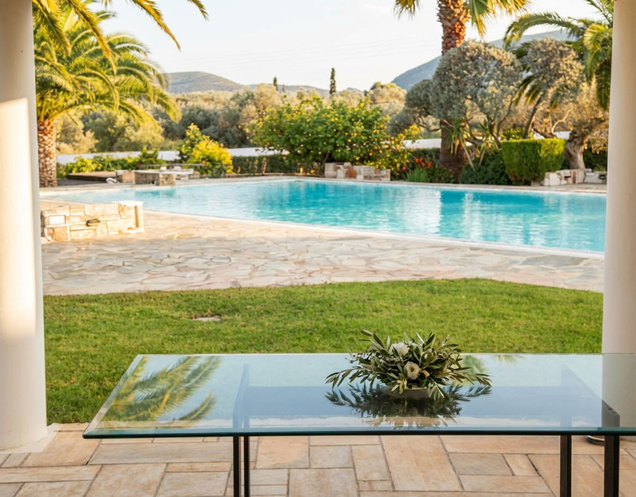 Porto Rafti Estate – Covered Terrace with Pool View Covered terrace with table overlooking the swimming pool and garden in Porto Rafti, Attica