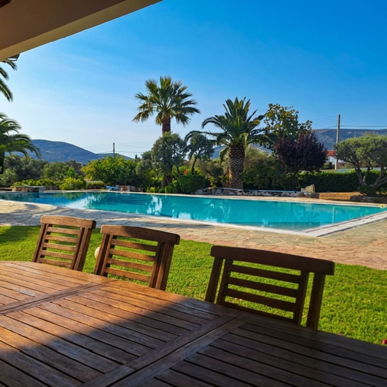 Outdoor deck seating overlooking the swimming pool and garden in Porto Rafti, Attica
