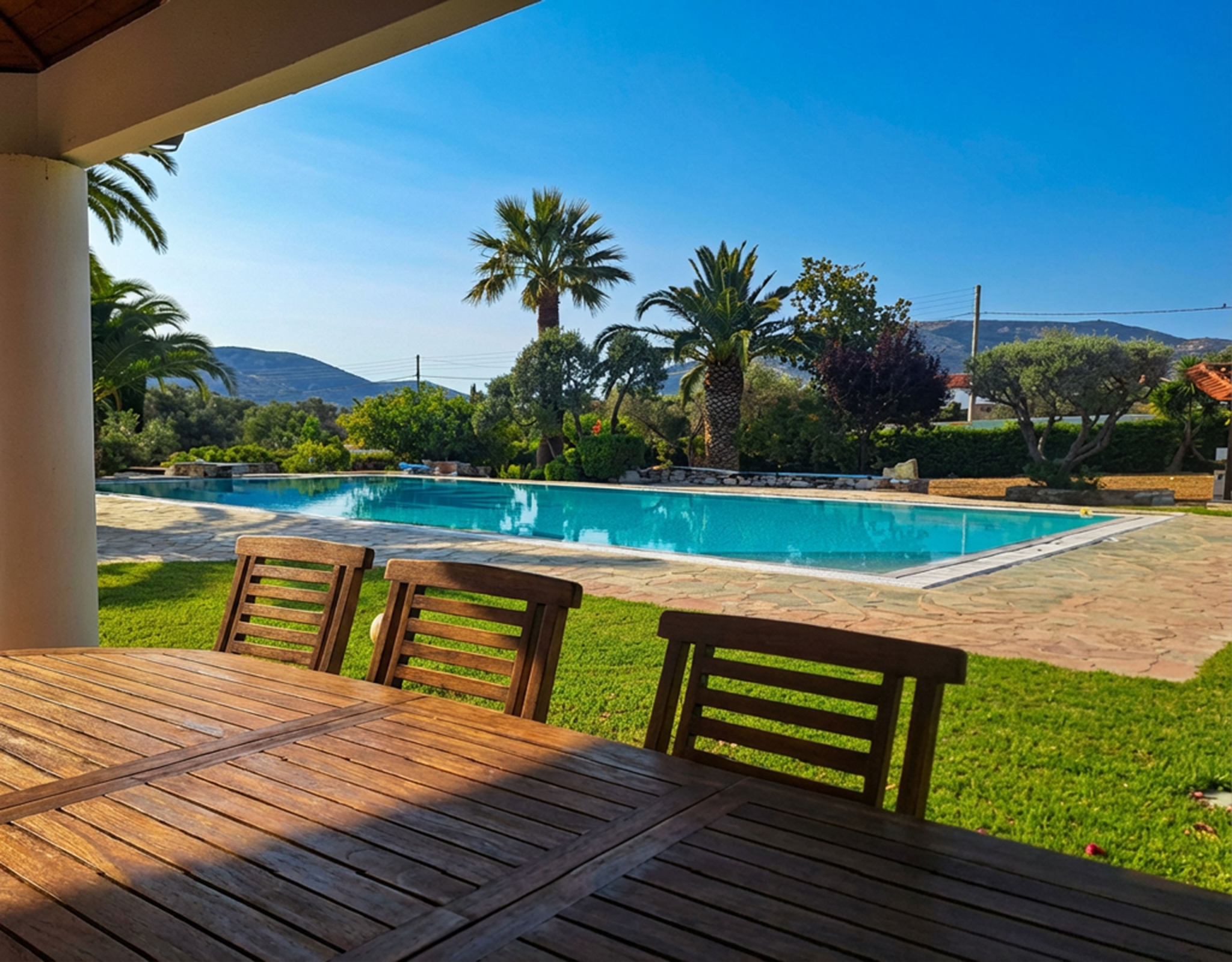 Porto Rafti Estate – Deck Seating with Pool View Outdoor deck seating overlooking the swimming pool and garden in Porto Rafti, Attica