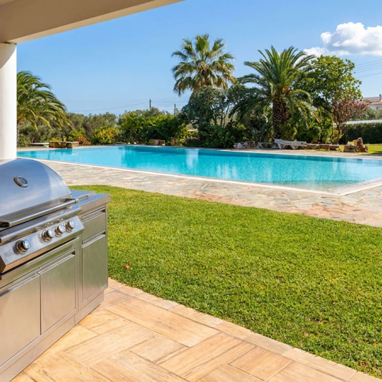 Outdoor barbecue terrace with pool and garden view at a private estate in Porto Rafti, Attica