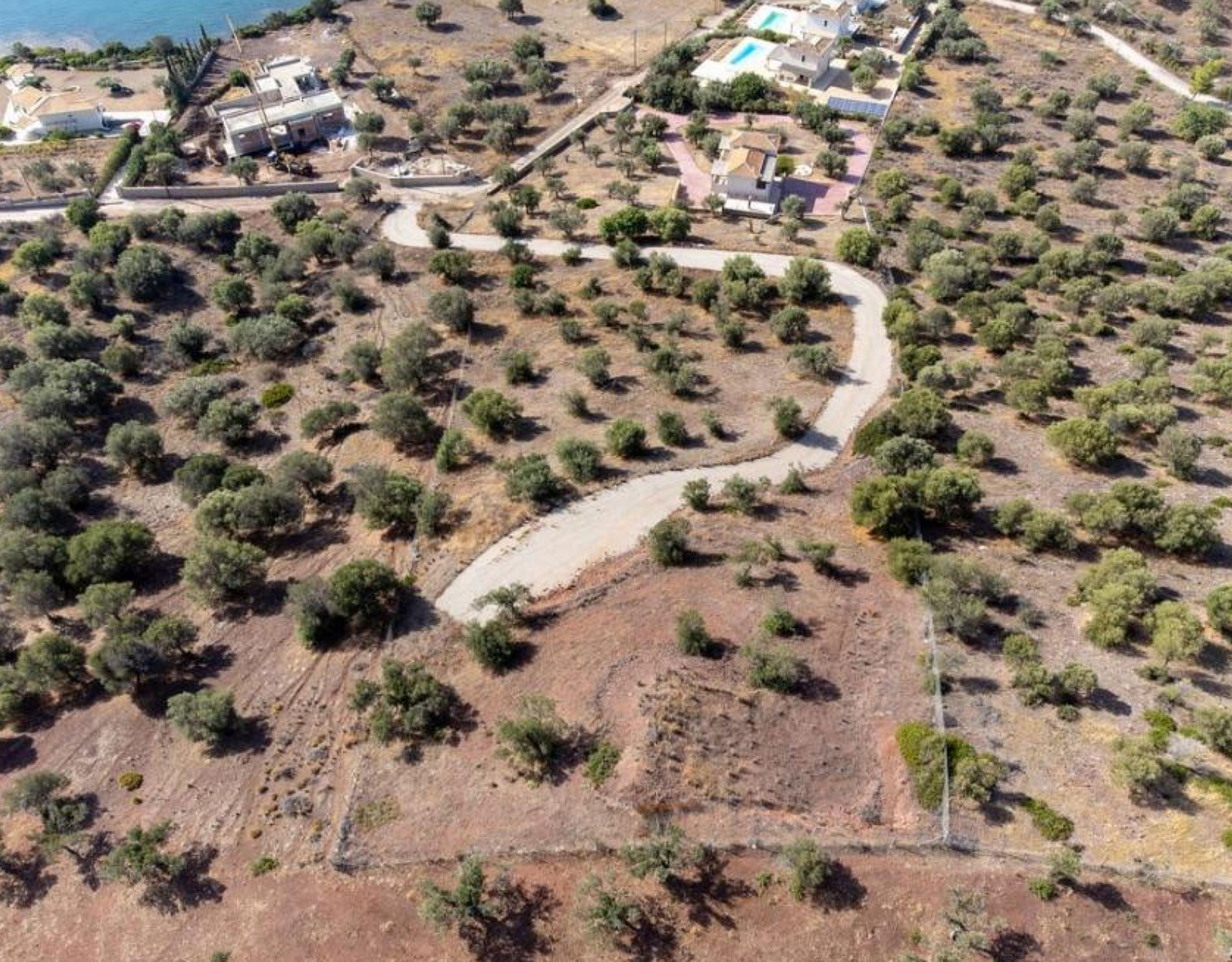 Ermioni Seaview Land Plot – Drone View With Nearby Residences Drone view of the plot area with road access and nearby residences, Ermioni, Greece
