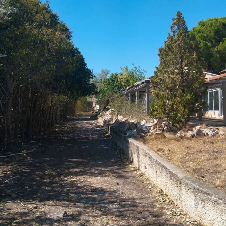 Land plot view with boundary wall and adjacent building structure, Pallini, Athens, Greece