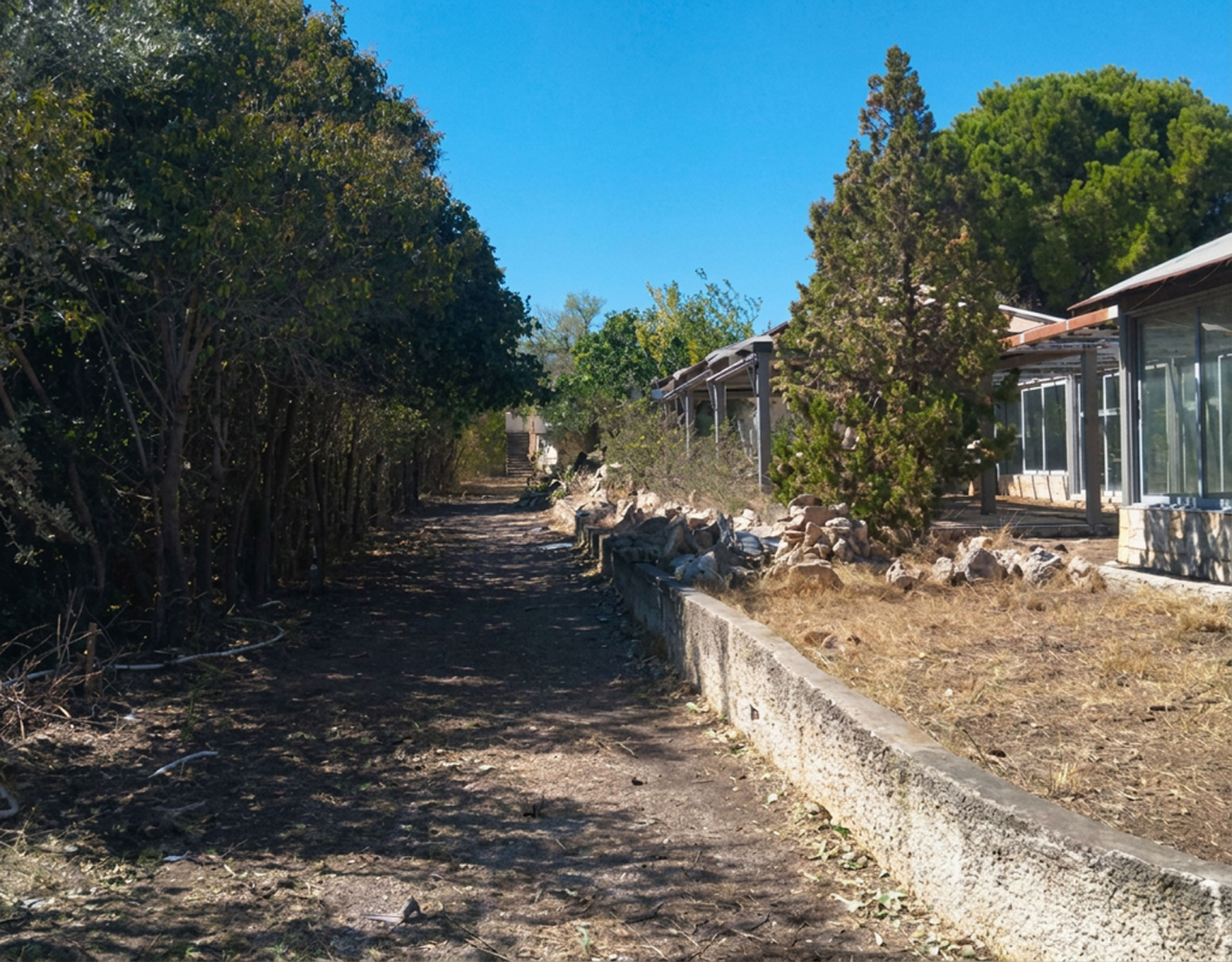 Pallini Mixed-Use Estate – Plot Boundary Wall And Building View Land plot view with boundary wall and adjacent building structure, Pallini, Athens, Greece