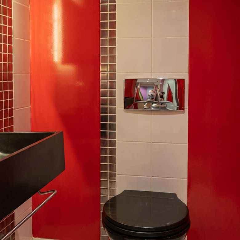 WC επισκεπτών με κόκκινες επιφάνειες, μαύρο νιπτήρα και μωσαϊκό πλακάκι σε εμπορικό χώρο στο κέντρο Θεσσαλονίκης