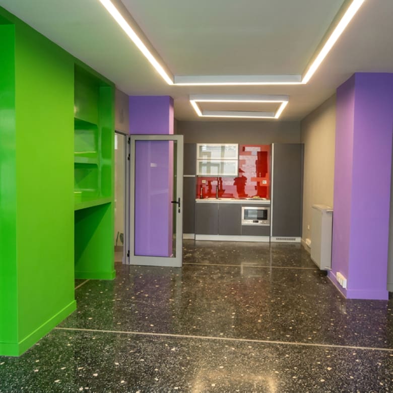 Open-plan εσωτερικός χώρος με ειδικό φωτισμό οροφής, ενσωματωμένα ράφια και κουζίνα στο βάθος σε εμπορικό ακίνητο στο κέντρο Θεσσαλονίκης