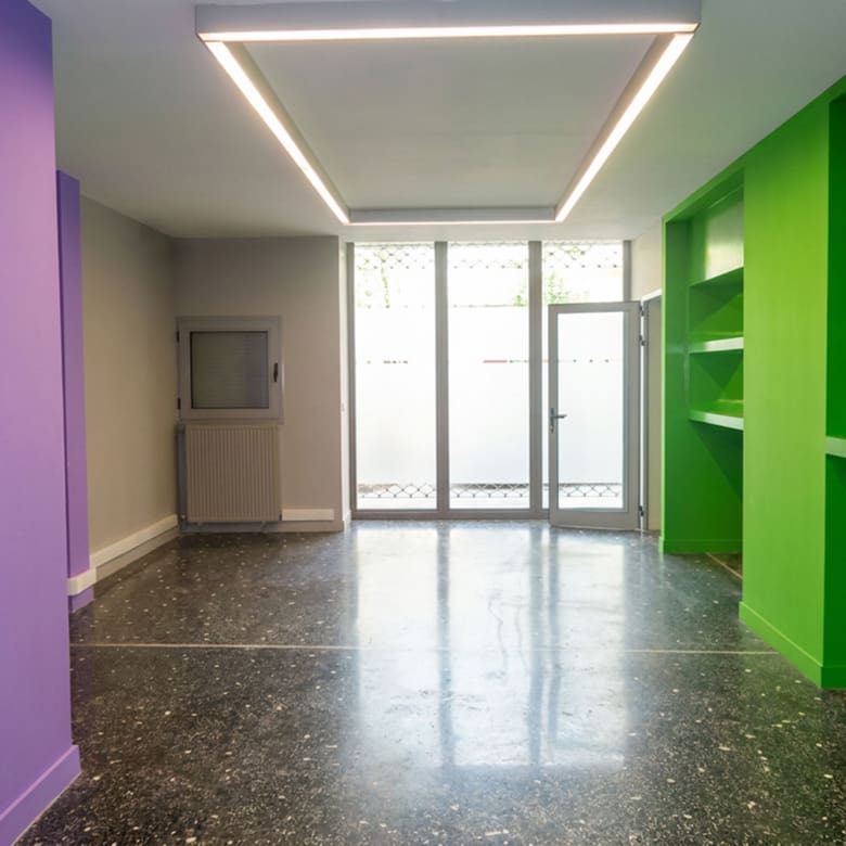 Open-plan εσωτερικός χώρος με ειδικό φωτισμό οροφής, μεγάλες γυάλινες πόρτες/βιτρίνα και ενσωματωμένα ράφια σε εμπορικό ακίνητο στο κέντρο Θεσσαλονίκης