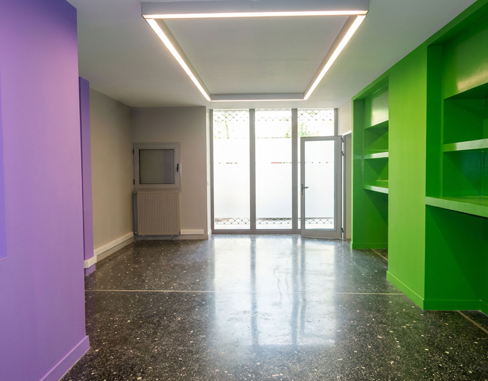 Open-plan εσωτερικός χώρος με ειδικό φωτισμό οροφής, μεγάλες γυάλινες πόρτες/βιτρίνα και ενσωματωμένα ράφια σε εμπορικό ακίνητο στο κέντρο Θεσσαλονίκης