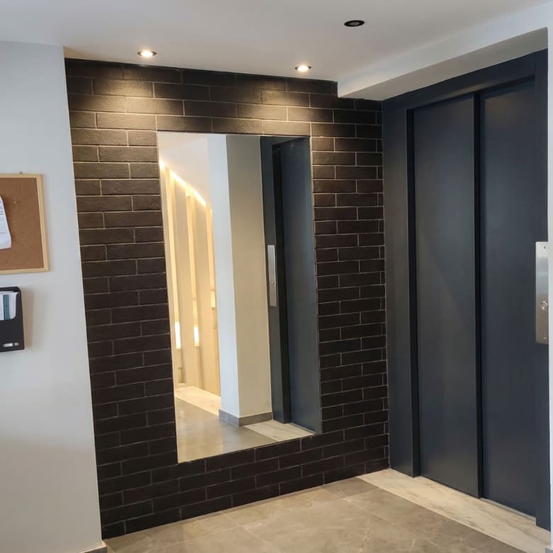 Modern building entrance lobby with elevator and decorative wall mirror Title: Building Entrance Lobby & Elevator